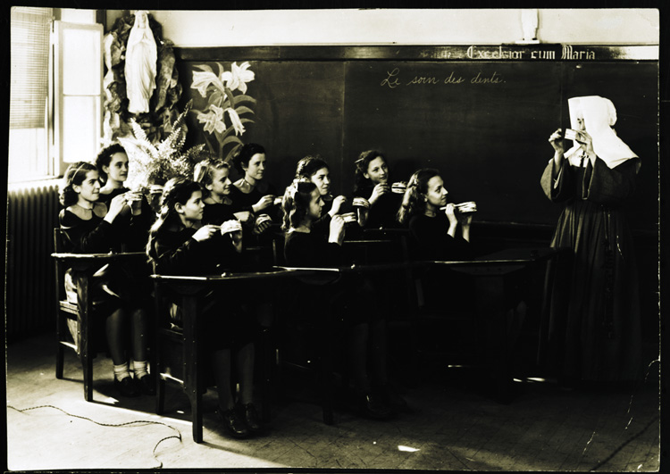 Reproduction d’une photographie d’une religieuse de la congr&eacute;gation des Filles de la sagesse et de ses &eacute;l&egrave;ves lors d’un cours d’hygi&egrave;ne sur les soins dentaires, &agrave; l’&eacute;cole Montfort, rue Dupuis, Vanier (Ontario), 1947.