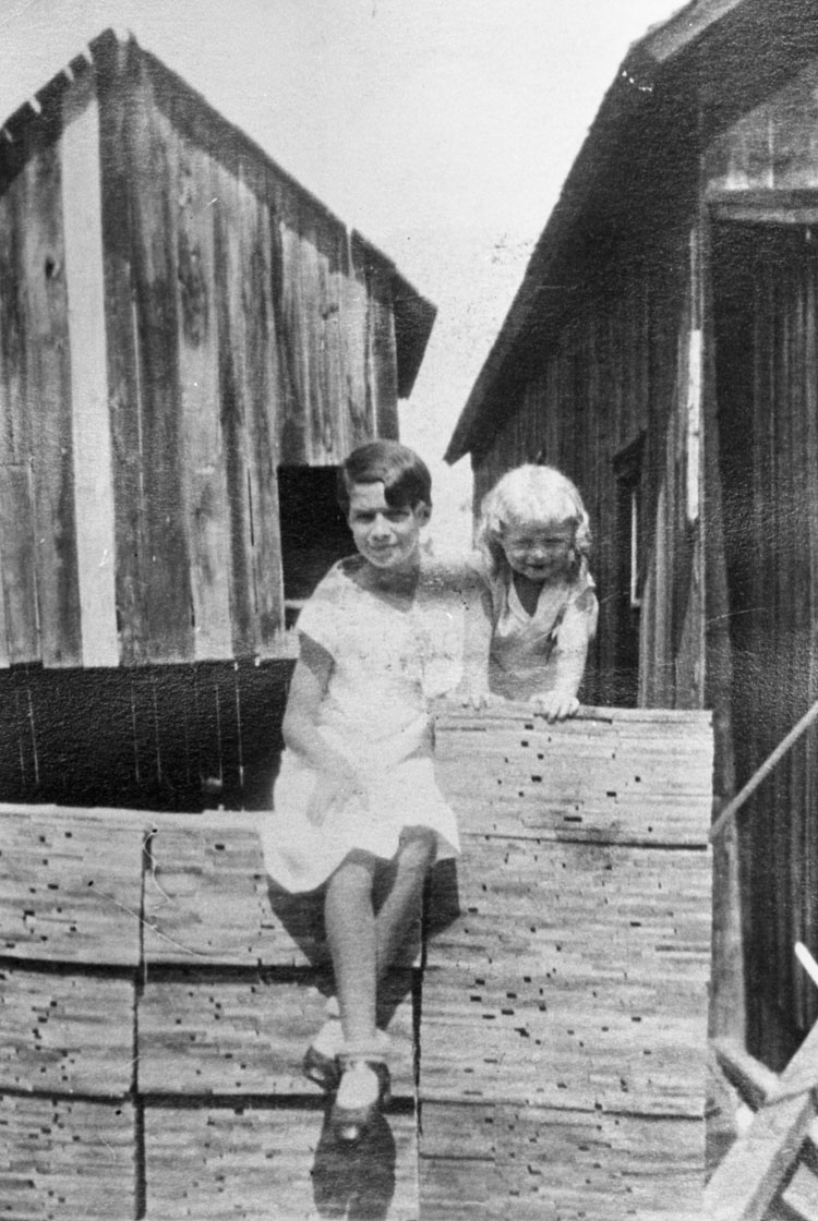 Reproduction d’une photographie de Evelyn Munroe et Roger Leroux sur des piles de bardeaux fabriqu&eacute;s au moulin &agrave; scie Munroe’s Mill, Green Valley (Ontario), ca 1931.