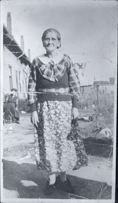 Reproduction d’une photographie de Marie Fortin, &eacute;pouse de Alphonse Marois, dans sa cour, Welland (Ontario), avant 1936.