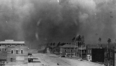 Reproduction d’une photographie de gens r&eacute;unis devant l’h&ocirc;tel Queens sur la sixi&egrave;me avenue &agrave; Cochrane &agrave; l’approche de l’incendie, 29 juillet 1911.